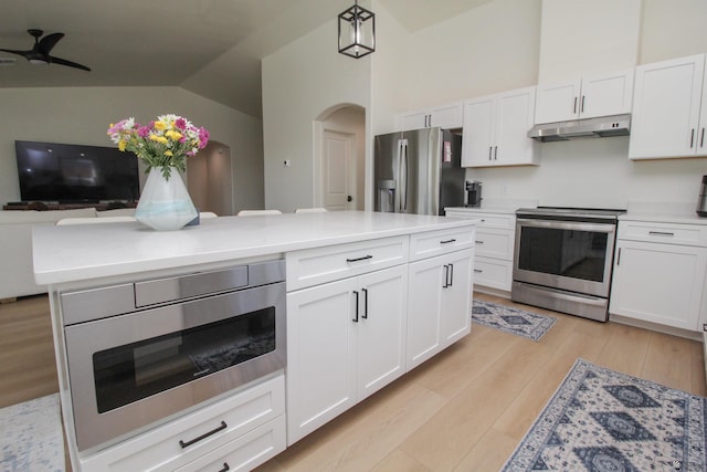 kitchen with appliances with stainless steel finishes, arched walkways, white cabinetry, lofted ceiling, and under cabinet range hood