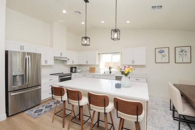 kitchen featuring visible vents, a kitchen bar, high vaulted ceiling, and stainless steel appliances