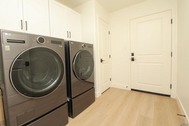 washroom with baseboards, cabinet space, light wood finished floors, and washing machine and clothes dryer