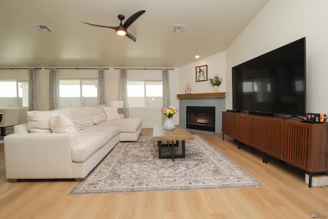 living area featuring ceiling fan, a brick fireplace, wood finished floors, and visible vents