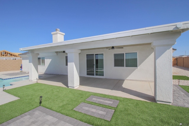 back of property with stucco siding, a fenced backyard, a patio area, a ceiling fan, and a yard