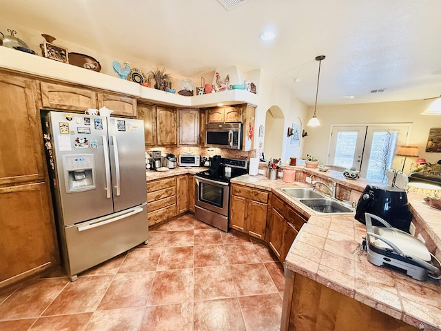 14340 E 49th Ln, Yuma, AZ 85367 - kitchen featuring visible vents, a peninsula, brown cabinets, a sink, and appliances with stainless steel finishes