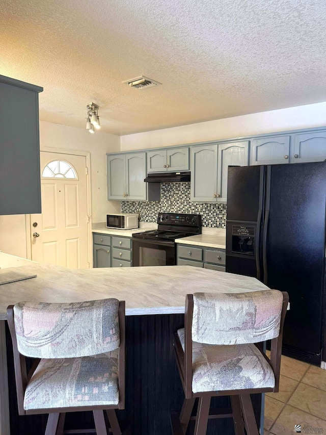 13458 E 53rd Ln, Yuma, AZ 85367 - kitchen featuring black appliances, under cabinet range hood, a peninsula, light countertops, and a kitchen bar