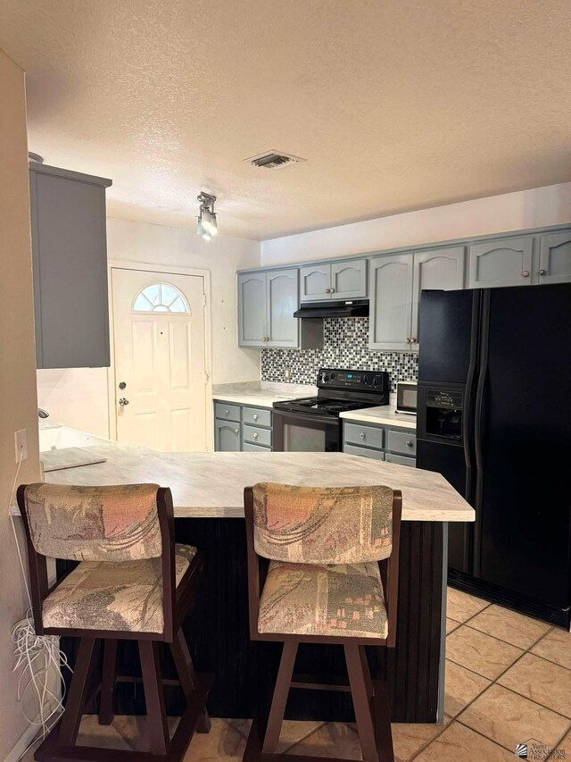 13458 E 53rd Ln, Yuma, AZ 85367 - kitchen with black appliances, light countertops, a kitchen breakfast bar, and gray cabinetry