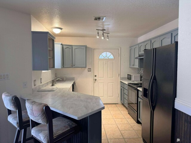 13458 E 53rd Ln, Yuma, AZ 85367 - kitchen with black appliances, a peninsula, gray cabinets, a breakfast bar, and a textured ceiling