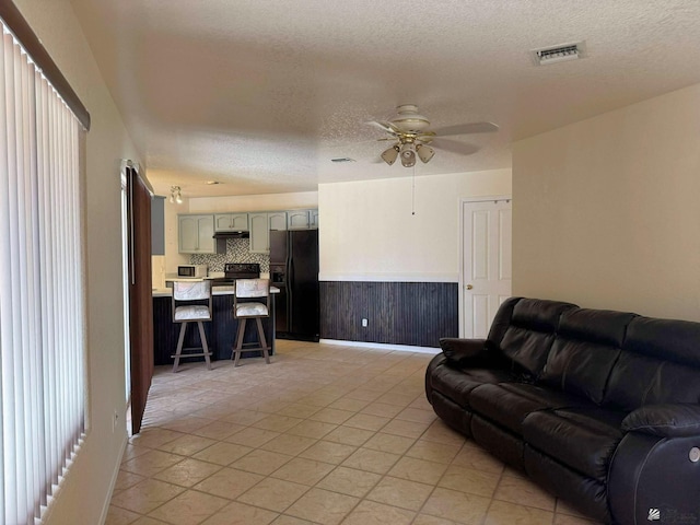 13458 E 53rd Ln, Yuma, AZ 85367 - living area with ceiling fan, a textured ceiling, a wainscoted wall, and light tile patterned flooring