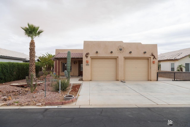 pueblo revival-style home with a garage, stucco siding, and concrete driveway