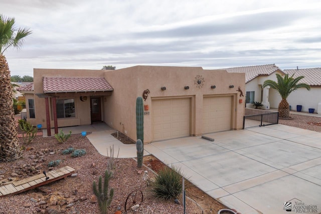adobe home featuring a tiled roof, an attached garage, driveway, and stucco siding