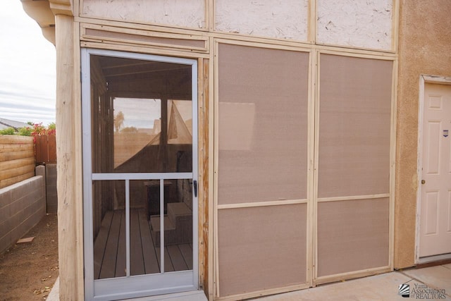 entrance to property with stucco siding and fence