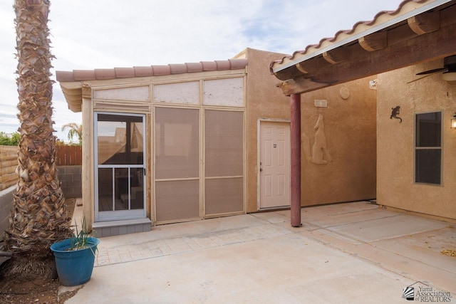 exterior space with ceiling fan, a patio area, stucco siding, and a tile roof