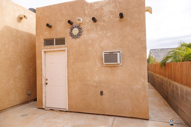 property entrance with stucco siding and fence