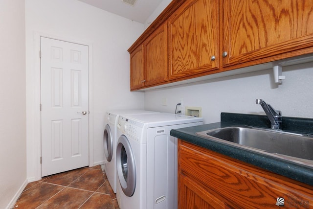 laundry room featuring baseboards, dark tile patterned flooring, separate washer and dryer, a sink, and cabinet space