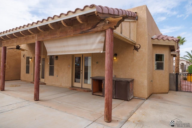 rear view of house featuring a ceiling fan, stucco siding, a patio area, and a tile roof