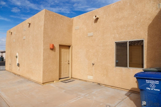 exterior space with a patio, visible vents, and stucco siding