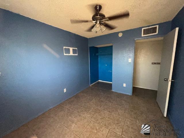 2232 W 19th St, Yuma, AZ 85364 - unfurnished bedroom with tile patterned floors, a closet, a textured ceiling, and ceiling fan