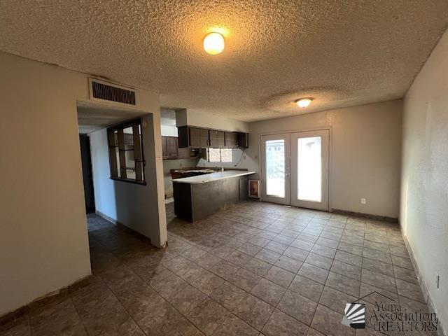 2232 W 19th St, Yuma, AZ 85364 - kitchen featuring a textured ceiling, a peninsula, light countertops, and dark brown cabinets