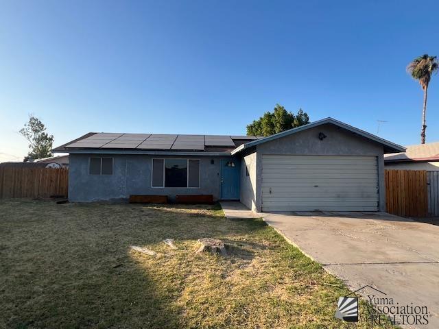 2232 W 19th St, Yuma, AZ 85364 - ranch-style house with a garage, concrete driveway, and roof mounted solar panels