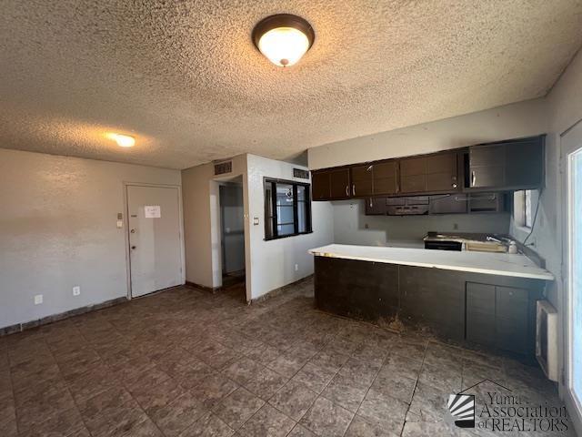 2232 W 19th St, Yuma, AZ 85364 - kitchen featuring a textured ceiling, a peninsula, light countertops, and dark brown cabinetry