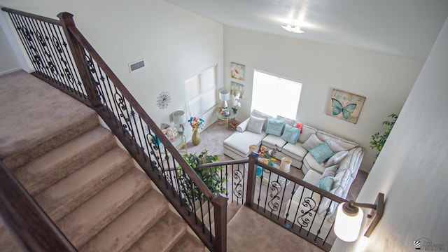 stairs featuring visible vents, carpet floors, and high vaulted ceiling