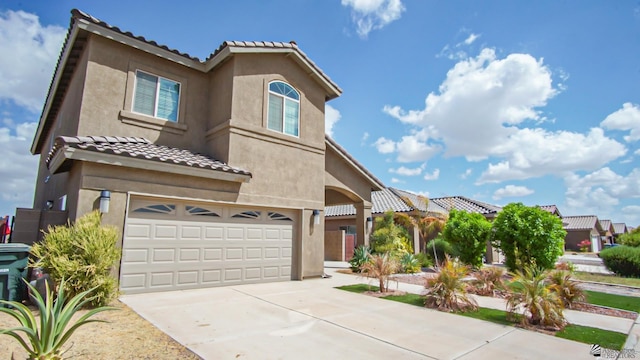 mediterranean / spanish-style house featuring stucco siding, driveway, a tile roof, and a garage