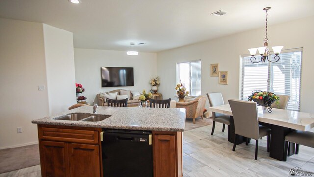 kitchen featuring visible vents, decorative light fixtures, light stone counters, a sink, and dishwasher