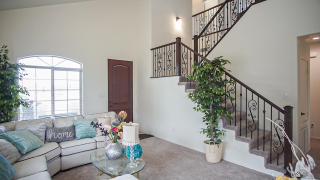 living area featuring stairs, a high ceiling, and carpet floors