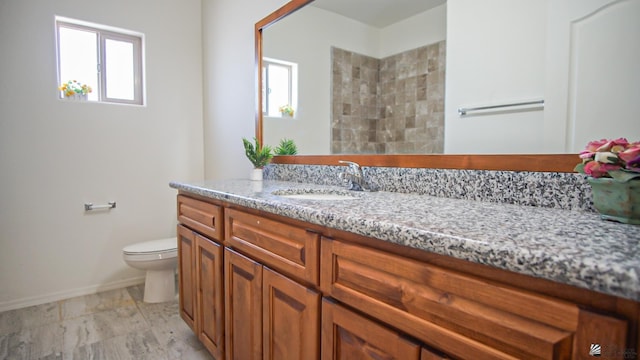 full bathroom with vanity, toilet, baseboards, and a wealth of natural light