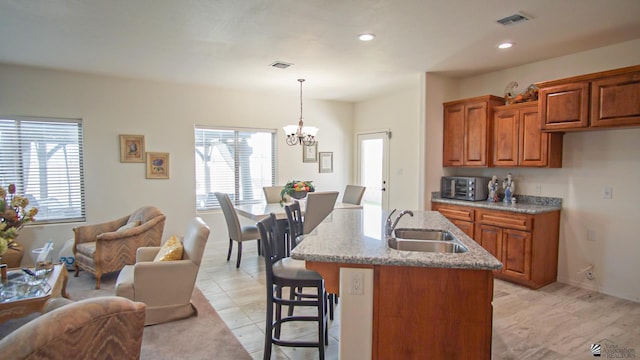 kitchen featuring open floor plan, brown cabinets, visible vents, and a sink