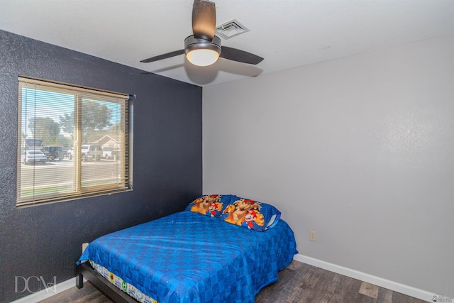 bedroom featuring visible vents, a ceiling fan, baseboards, and wood finished floors