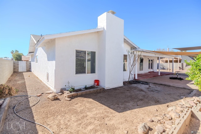 rear view of house featuring a patio, a fenced backyard, stucco siding, and a chimney