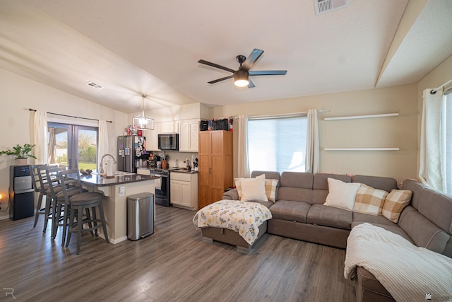 living area with a ceiling fan, vaulted ceiling, dark wood finished floors, and visible vents
