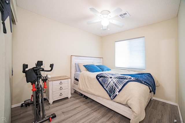 bedroom featuring baseboards, ceiling fan, wood finished floors, and visible vents