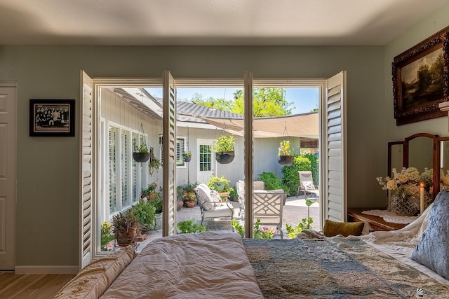 bedroom featuring wood finished floors, multiple windows, and access to exterior