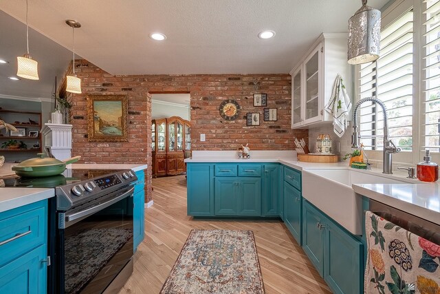 kitchen featuring a sink, brick wall, stainless steel appliances, glass insert cabinets, and blue cabinets