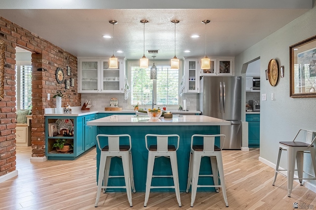kitchen featuring stainless steel appliances, blue cabinetry, a wealth of natural light, and light wood finished floors