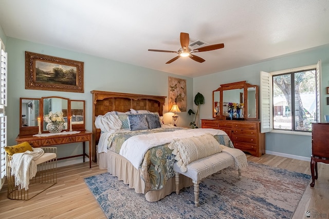 bedroom with a ceiling fan, baseboards, visible vents, and wood finished floors