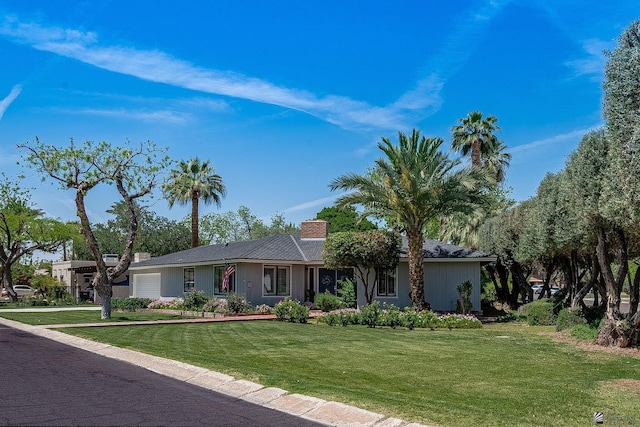 ranch-style home featuring a garage, a front yard, and a chimney