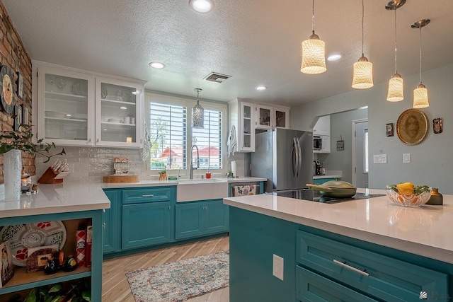 kitchen featuring visible vents, light countertops, a sink, light wood finished floors, and stainless steel appliances