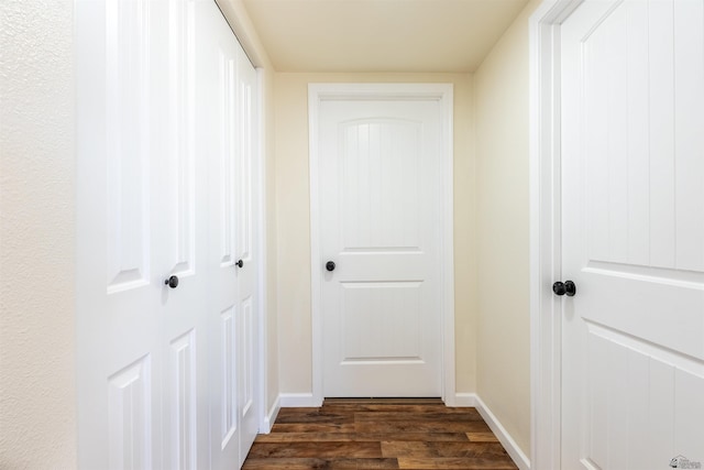 corridor featuring dark wood-style flooring and baseboards