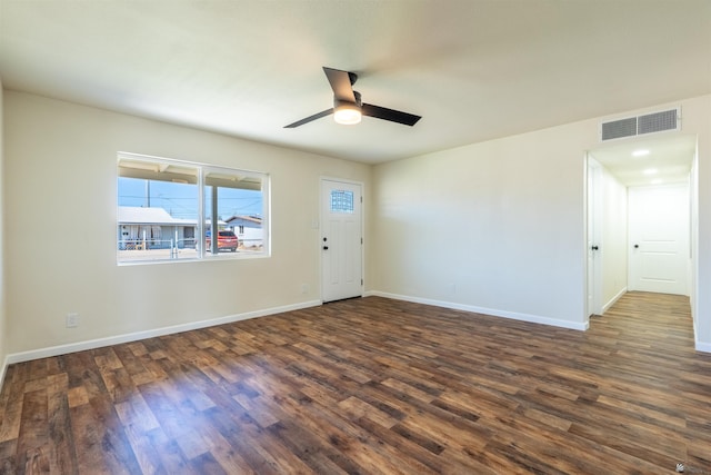 empty room with visible vents, a ceiling fan, dark wood-style flooring, and baseboards