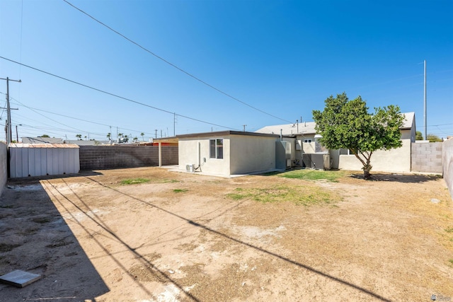 back of property with a fenced backyard, an outbuilding, and stucco siding