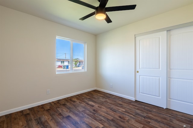 unfurnished bedroom featuring baseboards, a ceiling fan, dark wood-style floors, and a closet