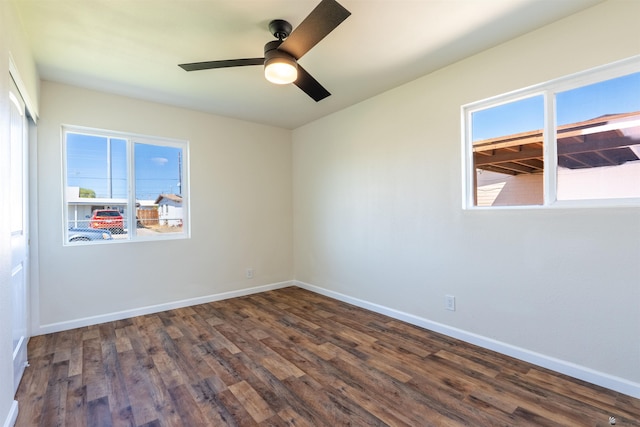 empty room with baseboards, ceiling fan, and dark wood-type flooring