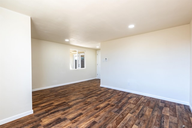 empty room with dark wood finished floors, baseboards, and recessed lighting