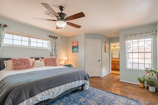 bedroom featuring baseboards, connected bathroom, finished concrete flooring, and ceiling fan
