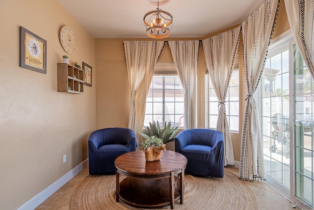 living area with a chandelier, healthy amount of natural light, and baseboards