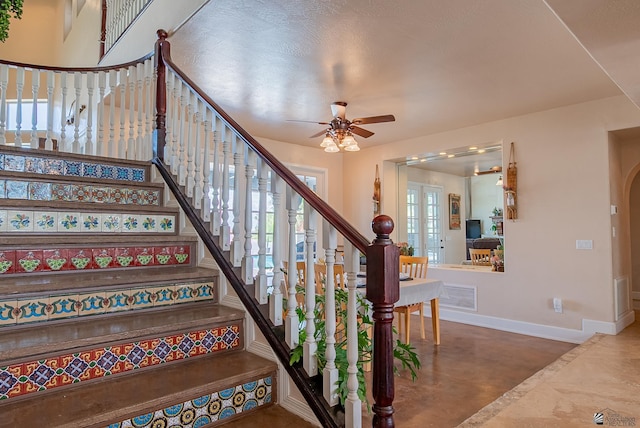 stairway featuring baseboards, ceiling fan, and arched walkways