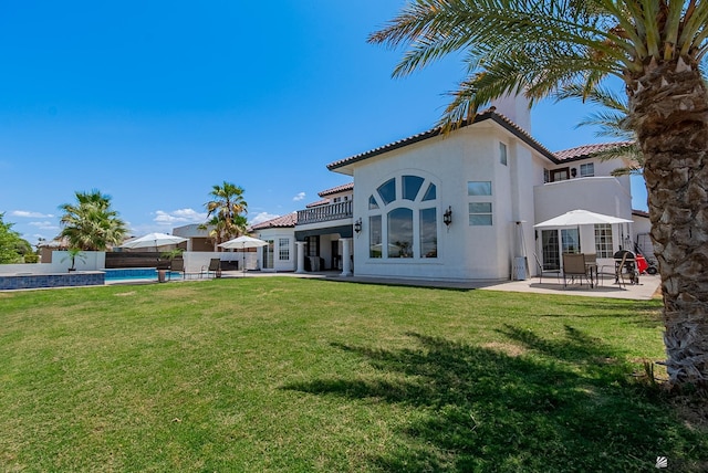 rear view of house with a tile roof, a patio area, stucco siding, and an outdoor pool