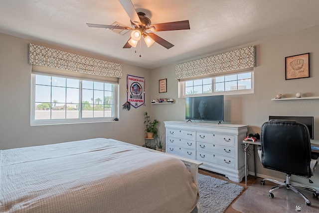 bedroom with an office area, baseboards, and ceiling fan