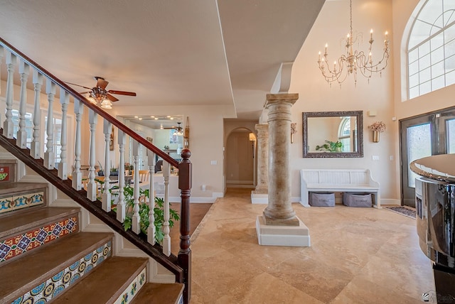 entryway featuring arched walkways, ceiling fan, baseboards, and a chandelier
